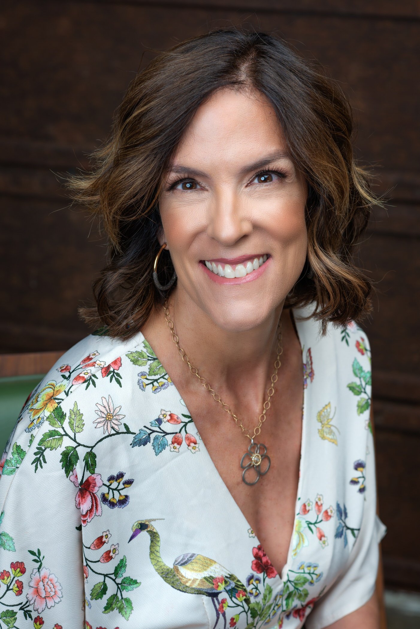 Artistic Emages High end branding photographer Dallas executive portrait of a confident woman in floral blouse, styled for approachable authority and premium brand presence.